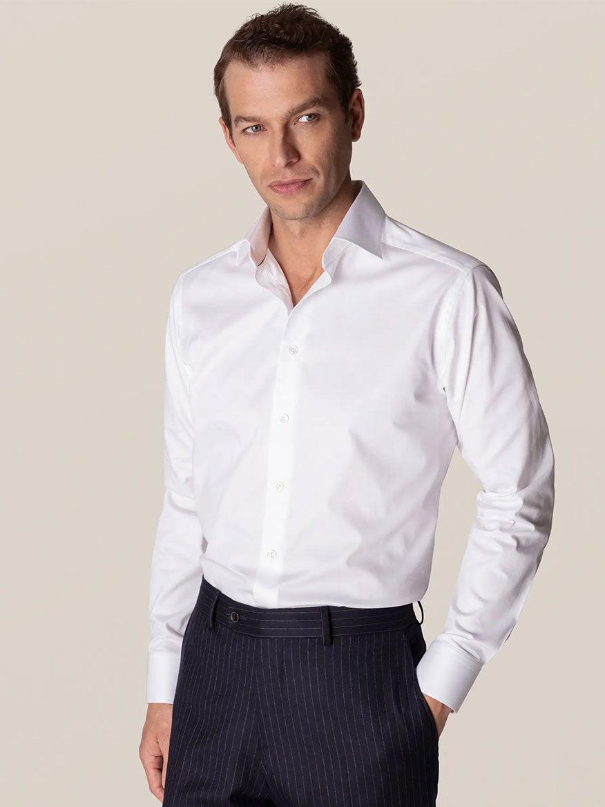 A man wearing a white Eton Slim Fit White Stretch Twill Dress Shirt and pinstripe trousers posing confidently.