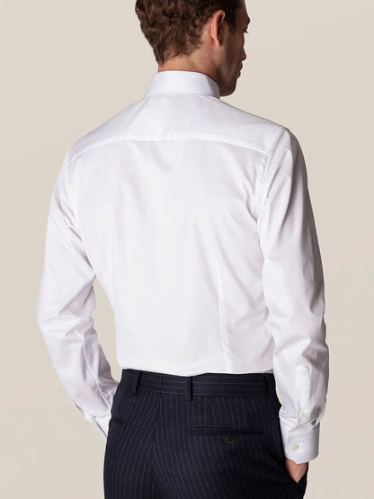 Man wearing an Eton Contemporary Fit White Stretch Twill Dress Shirt paired with pinstriped trousers, viewed from behind.