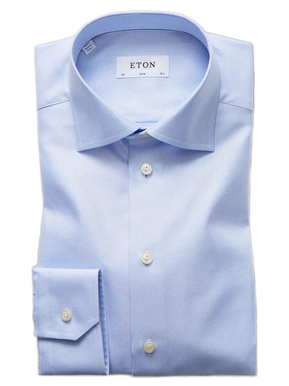 A neatly folded Eton Slim Fit Light Blue Textured Twill Dress Shirt with white buttons and an “ETON” label inside the collar.