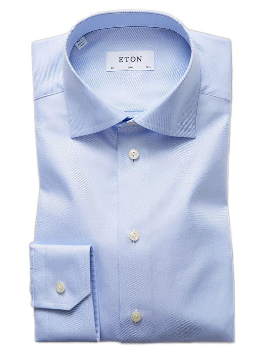 A neatly folded Eton Slim Fit Light Blue Textured Twill Dress Shirt with white buttons and an “ETON” label inside the collar.