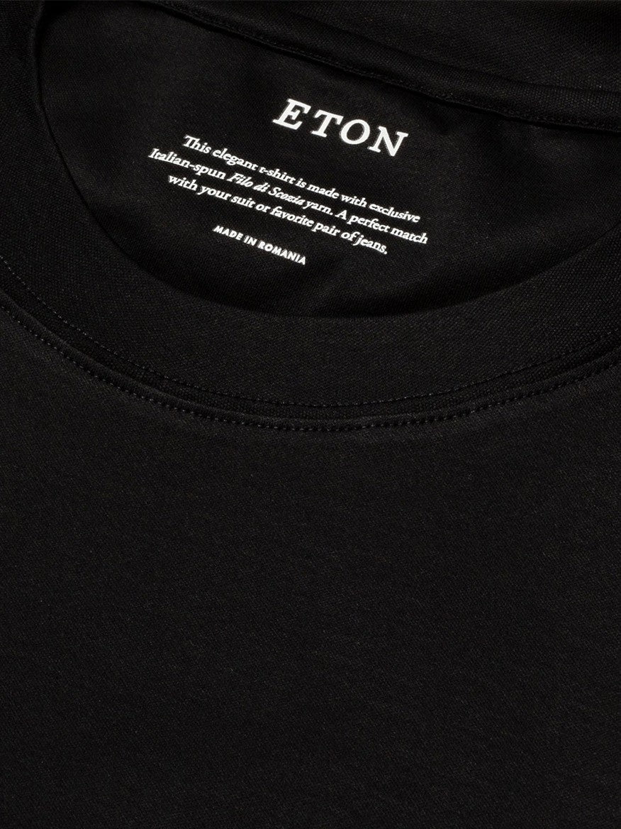 Close-up of a black Eton Filo di Scozia T-shirt label with white text detailing the brand, shirt style, and fabric comfort.