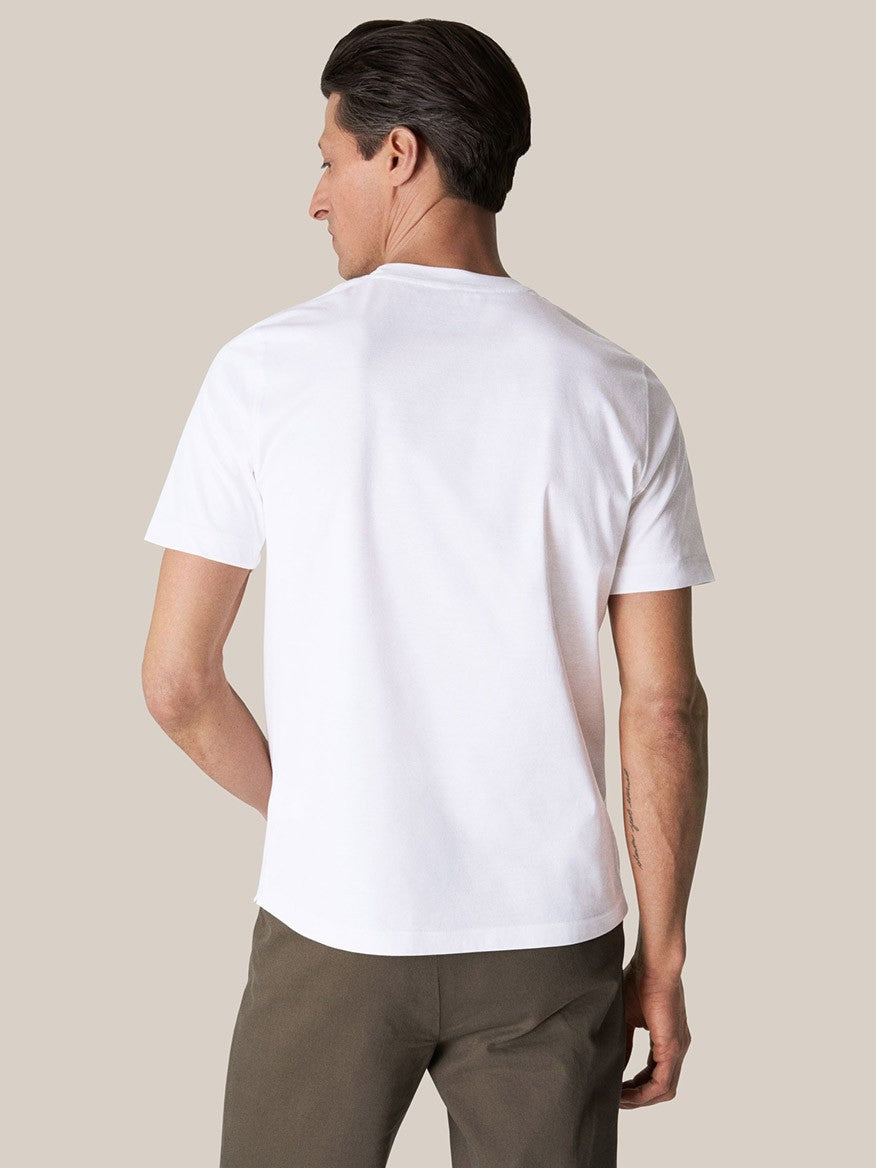 Man wearing a luxurious Eton Filo di Scozia white t-shirt and brown trousers seen from behind.