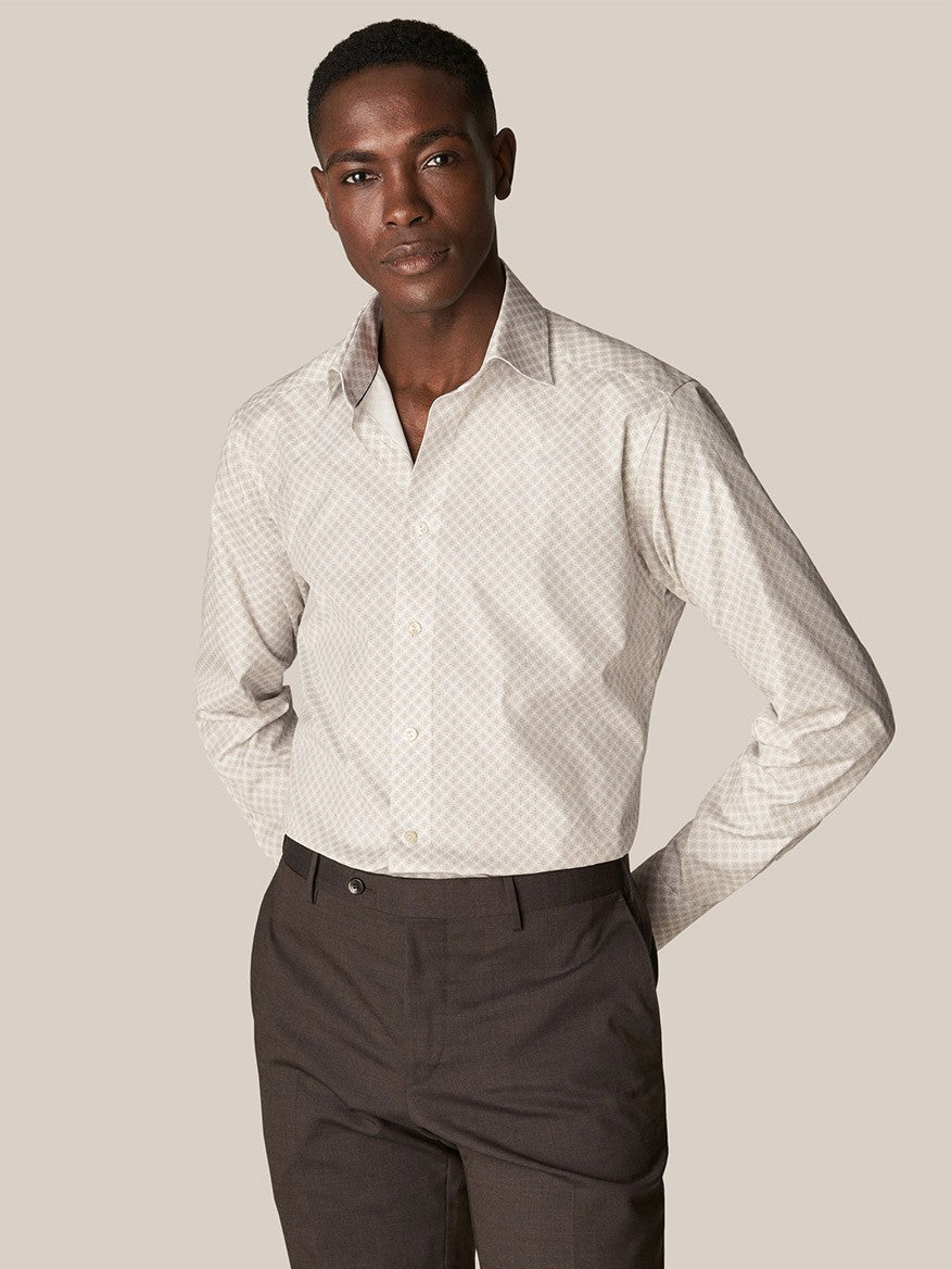 A man in Eton's Brown Signature Poplin Shirt in Medallion Print and dark trousers stands with one hand in his pocket, looking at the camera.