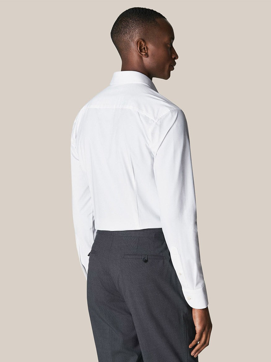 A man viewed from the back, wearing a Eton White Four-Way Stretch Shirt and dark trousers.