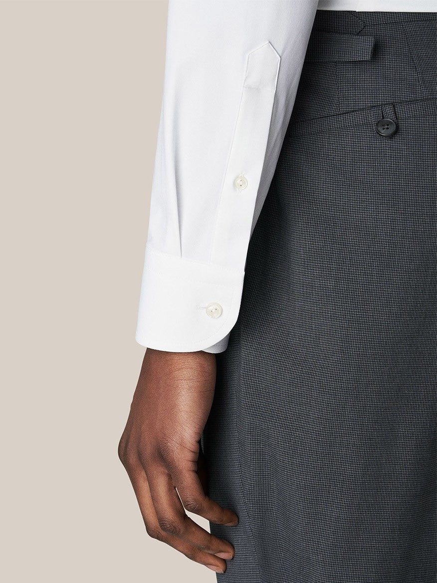 Close-up of a person wearing an Eton White Four-Way Stretch Shirt with a wide spread collar and grey trousers, with hand resting by their side.