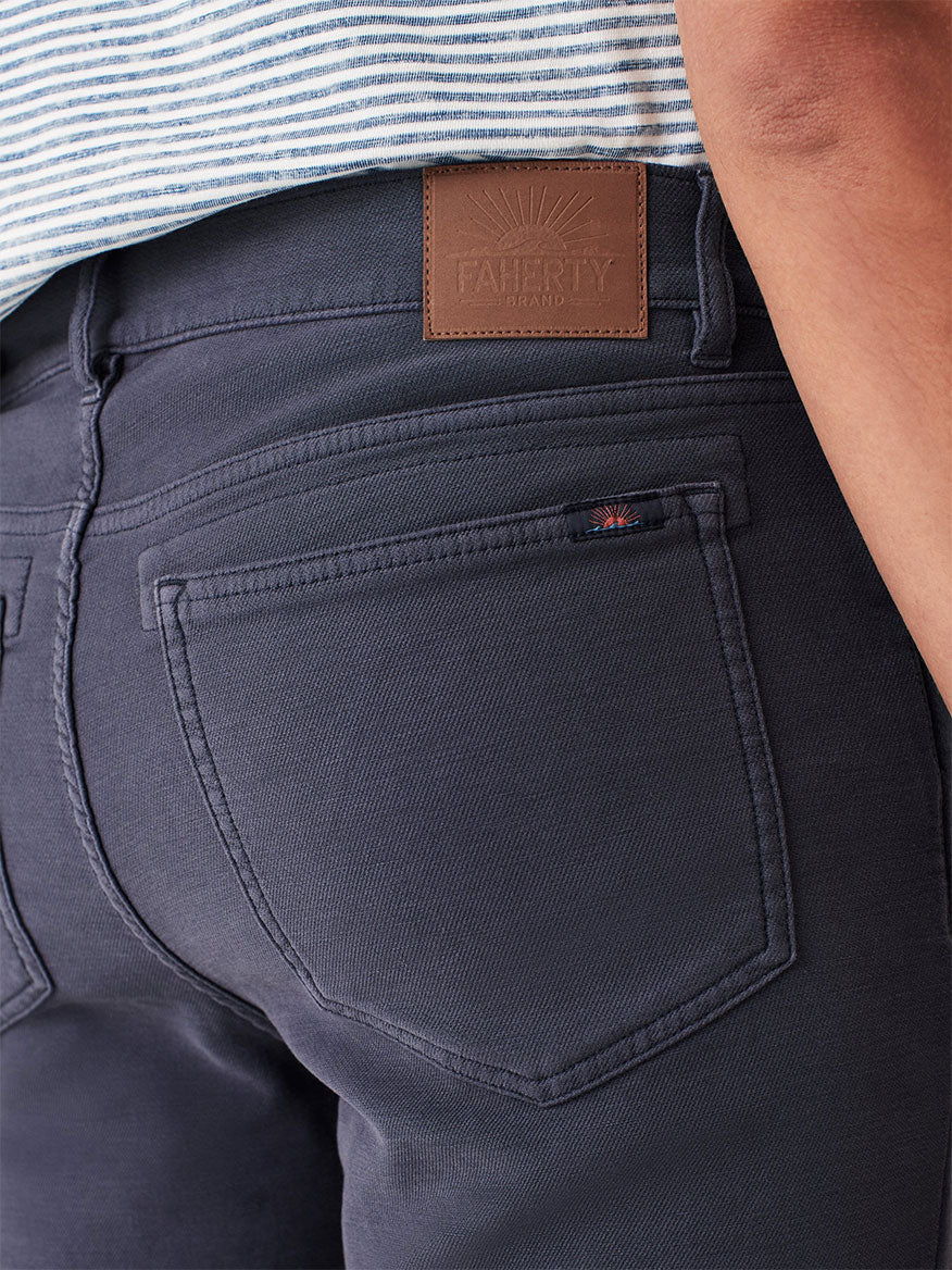 A person wearing their favorite Faherty Brand Stretch Terry 5-Pocket Pant in Navy with a leather label.