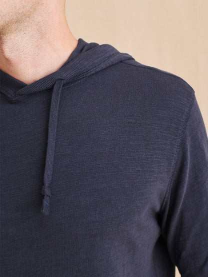 A man wearing a Faherty Brand Slub Cotton Hoodie in Blue Nights made of organic cotton.