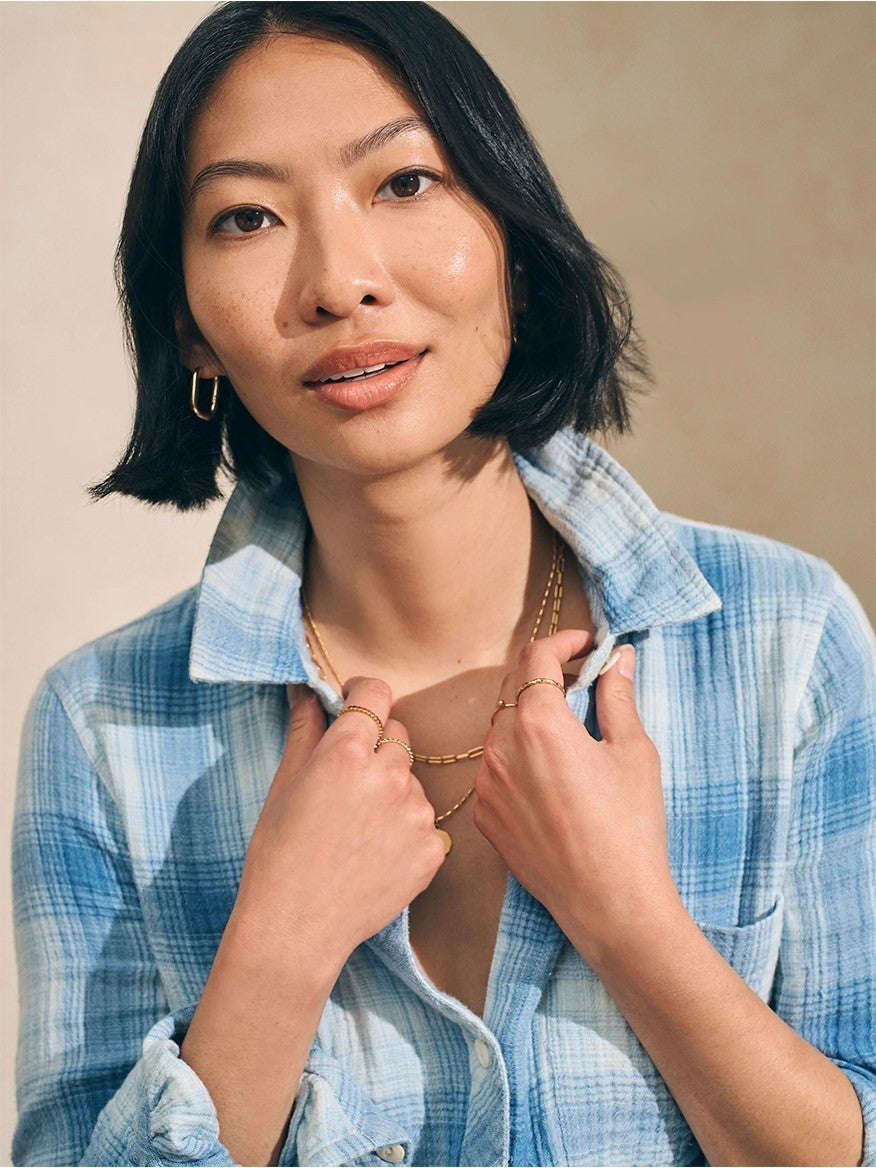 A woman in a Faherty Brand Malibu Shirt in Indigo Plaid is posing for a photo.