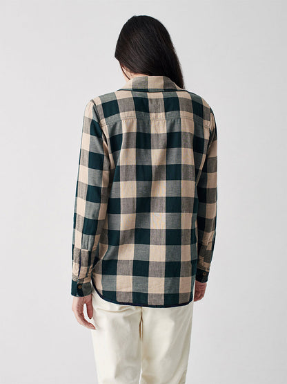 Rear view of a person wearing Faherty's Classic Reversible Shirt in Blackwatch plaid, paired with white pants, standing against a white background.