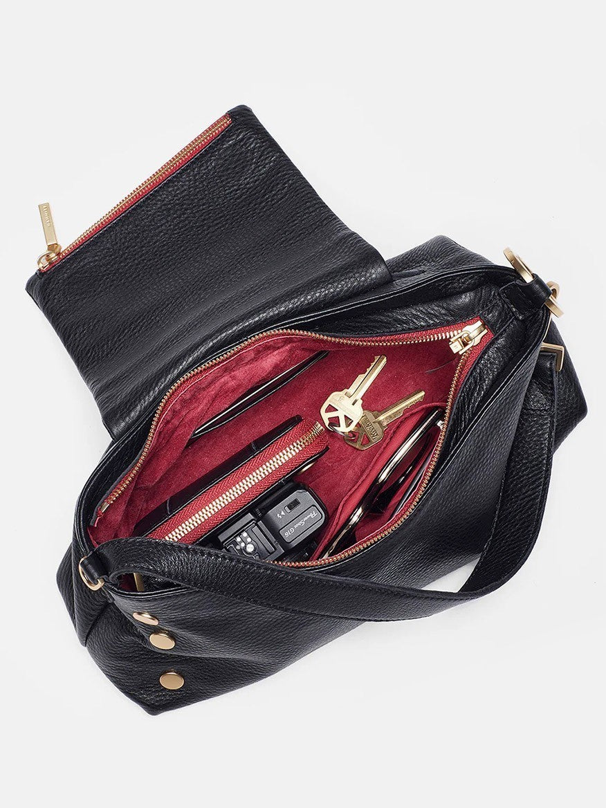A black pebbled leather Hammitt Los Angeles VIP Satchel in Black/Brushed Gold with a red interior is open, revealing keys, a pen, a key fob, and a pair of glasses inside. Hidden within the sleek design is the convenient magnetic cell pocket for easy access.