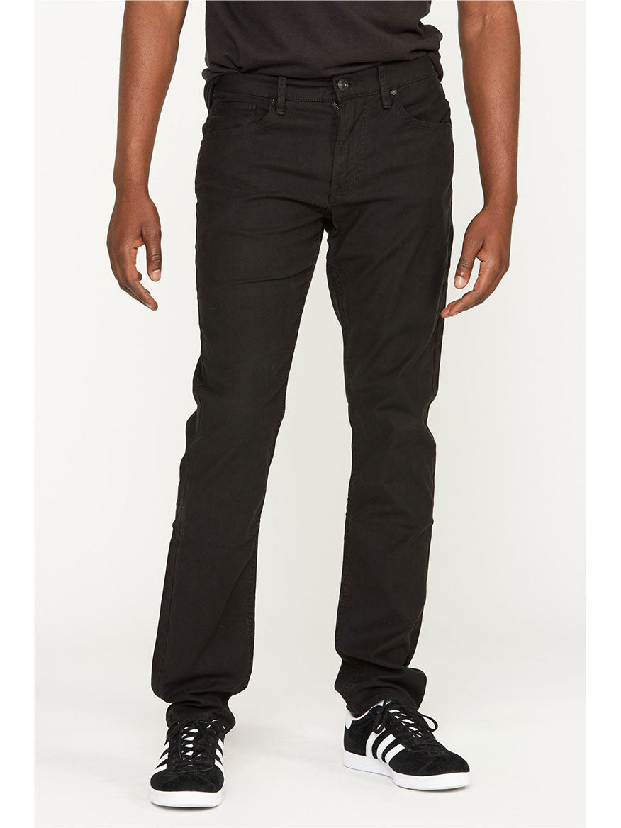A person wearing Hudson Blake Slim Straight Twill Pants in Black and black sneakers.