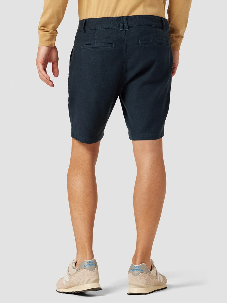 A person from behind wearing navy blue Hudson Chino Shorts in Night Blue and beige sneakers.