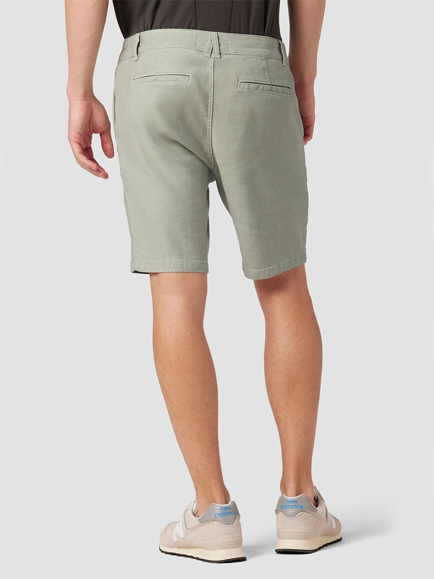 A warm weather warrior standing, showcasing a pair of Hudson Chino Shorts in Shell and casual sneakers from the back view.