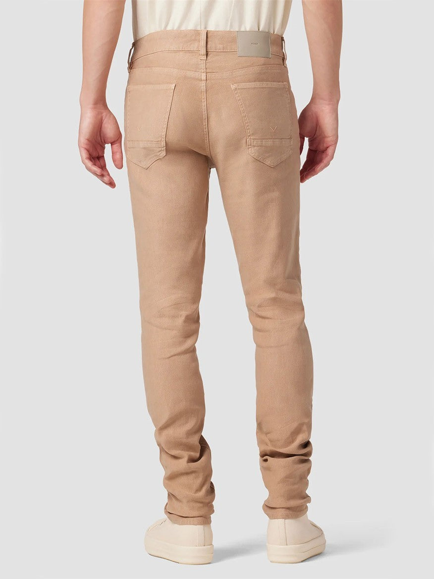 Rear view of a person wearing Hudson Blake Slim Straight Twill Pant in Latte and white sneakers, focusing on the fit and pocket details.