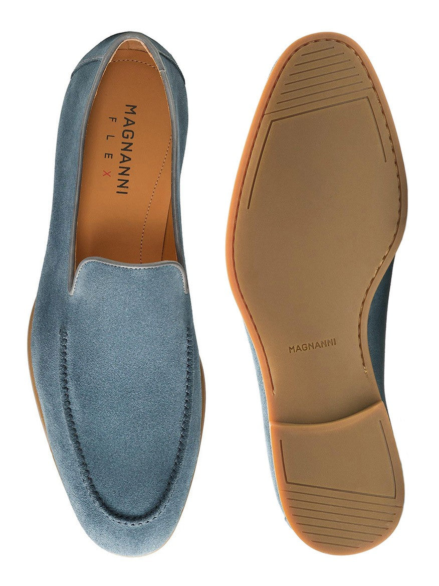 The Magnanni Lecera in Indigo Suede is displayed, featuring a top view of one venetian apron toe loafer and the tan rubber sole, showcasing the flexible design of this elegant dress shoe.