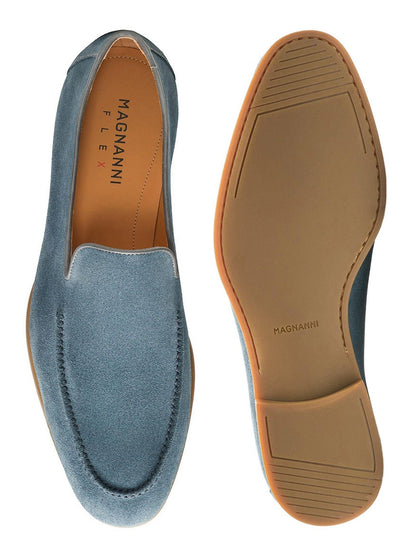 The Magnanni Lecera in Indigo Suede is displayed, featuring a top view of one venetian apron toe loafer and the tan rubber sole, showcasing the flexible design of this elegant dress shoe.