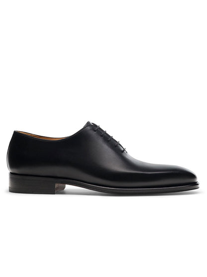 The Magnanni Crucero in Black is a whole cut Oxford dress shoe featuring black leather, closed lacing, Bologna construction, and a low stacked heel, shown in profile on a white background.