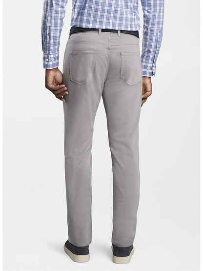 A man wearing Peter Millar Ultimate Sateen Five-Pocket Pant in Gale Grey and a blue checkered shirt, viewed from the back.