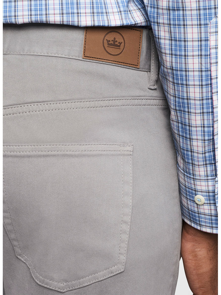 Close-up of a person wearing Peter Millar Ultimate Sateen Five-Pocket Pant in Gale Grey and a plaid shirt with a leather patch on the waistband.
