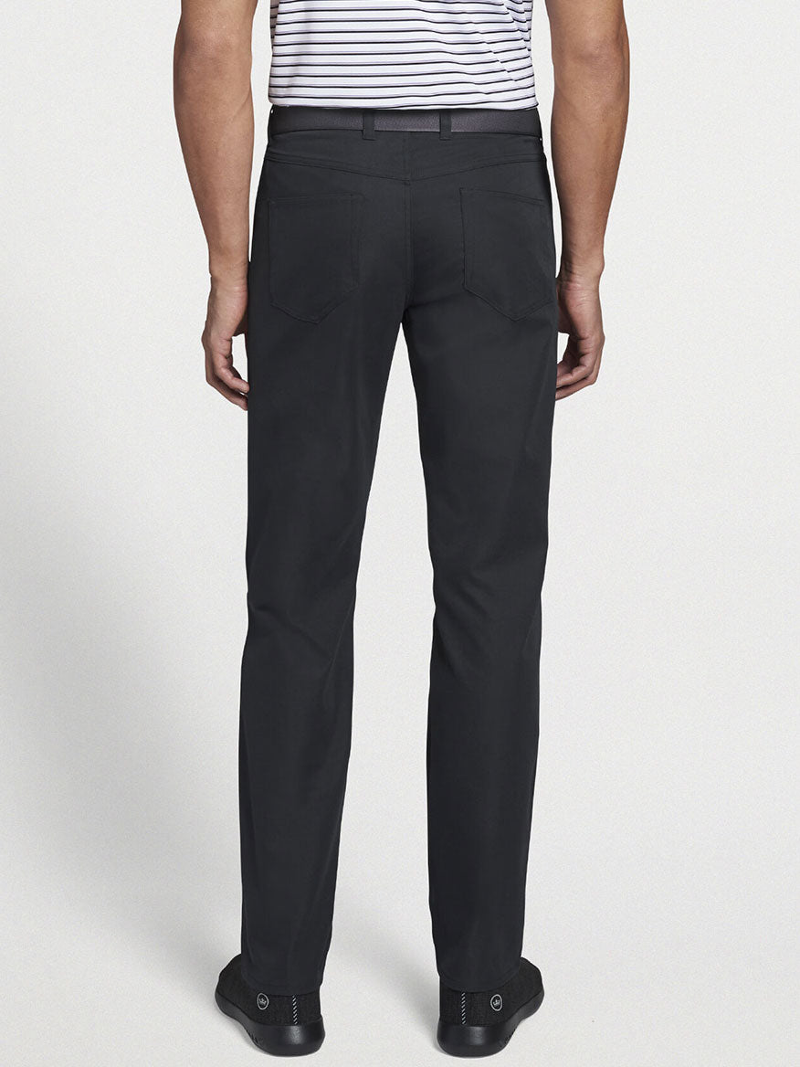 A person is shown from the back wearing a black and white striped shirt, Peter Millar Performance Five-Pocket Pant in Black, and sleek black shoes.