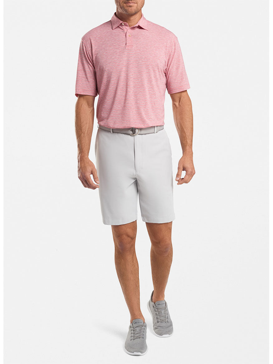 Man wearing a pink polo shirt and moisture wicking Peter Millar Salem High Drape Performance Short in British Grey with grey shoes.