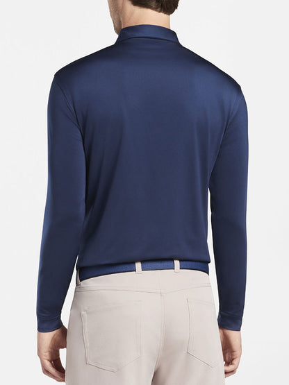 The back view of a man wearing a Peter Millar Solid Stretch Jersey Long Sleeve Polo in Navy.