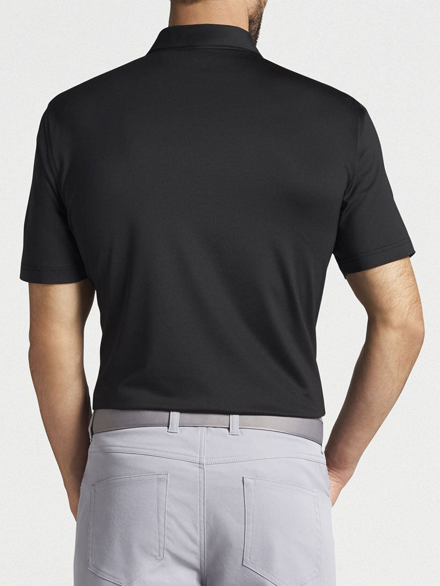 The back view of a man wearing a Peter Millar Solid Performance Jersey Polo in Black made with moisture-wicking fabric.