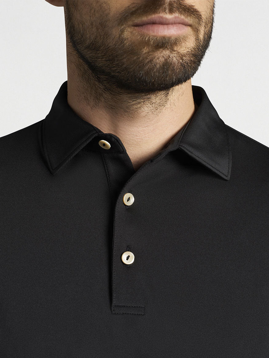 A man wearing a Peter Millar Solid Performance Jersey Polo in Black.