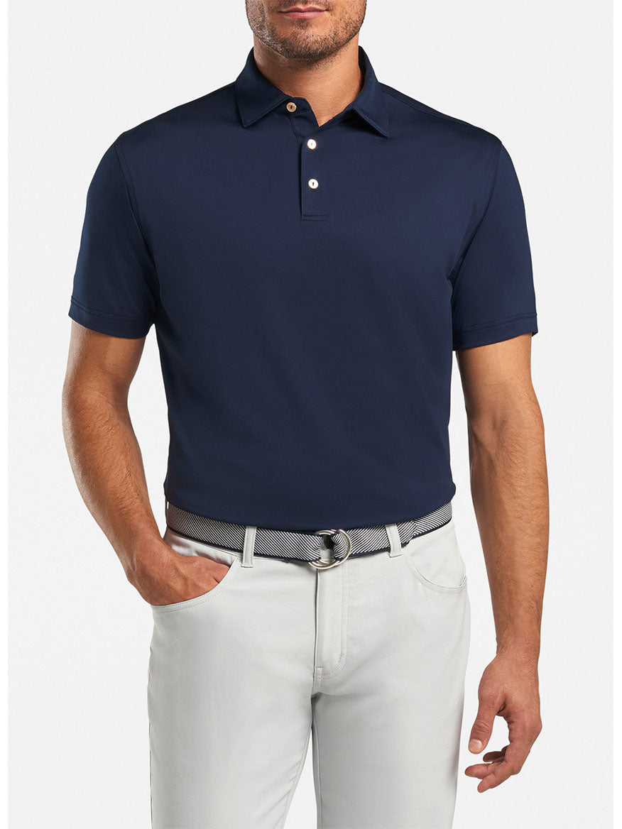 A man wearing a Peter Millar Solid Performance Jersey Polo in Navy and white pants.
