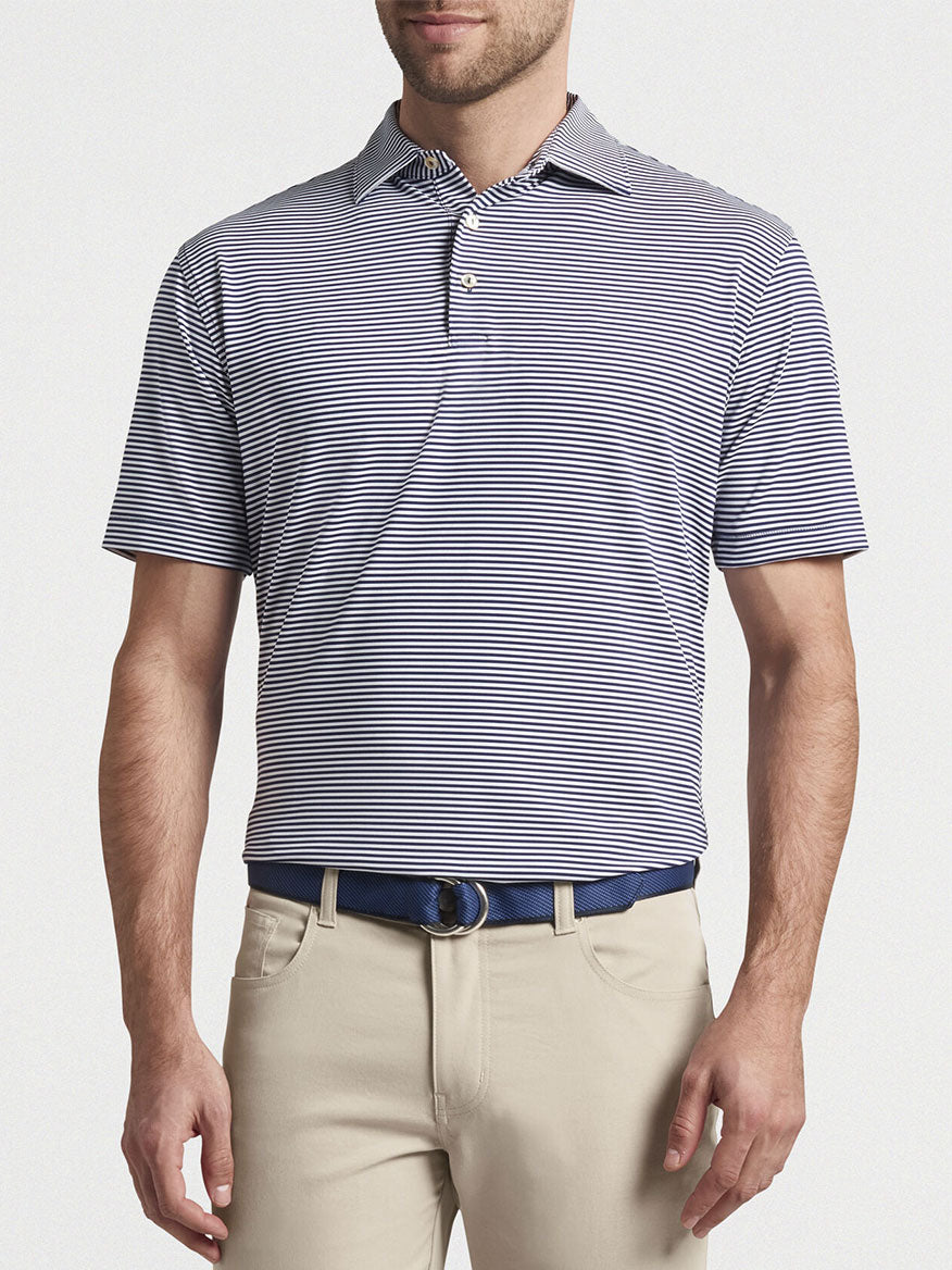 Man wearing a Peter Millar Hales Performance Jersey Polo in Navy with UPF 50+ sun protection and khaki trousers.