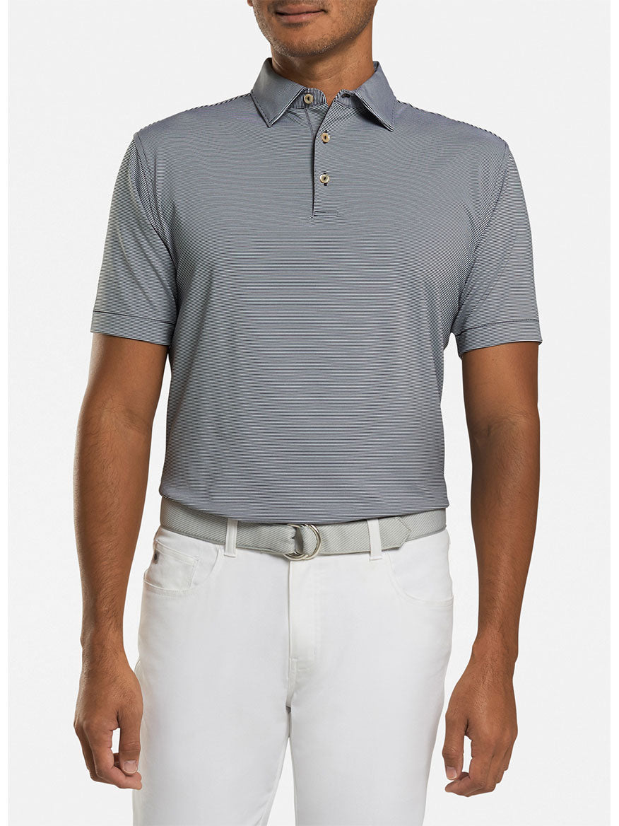 A person is wearing a black Peter Millar Jubilee Stripe Performance Polo with white pants and a gray belt, standing against a plain background.