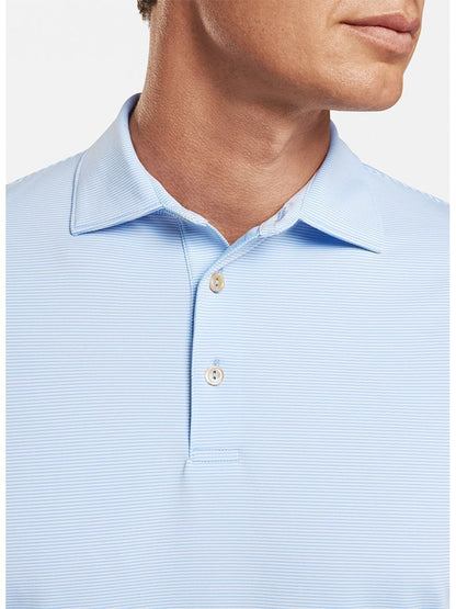A man wearing a Peter Millar Jubilee Stripe Performance Polo in Cottage Blue, a lightweight fabric, light blue polo shirt.