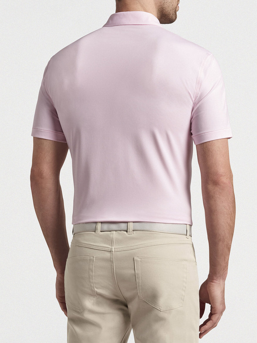 The back view of a man wearing a Peter Millar Jubilee Stripe Performance Polo in Palmer Pink.