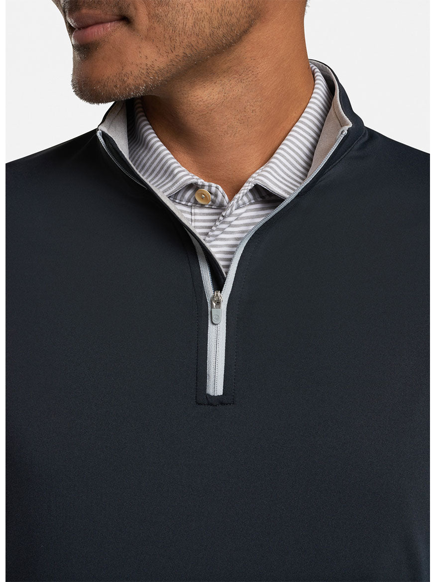 A man wearing a Peter Millar Perth Performance Quarter-Zip in Black, a performance-focused black and white striped half-zip sweater.