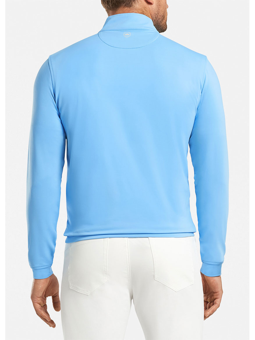 Man wearing a Peter Millar Perth Performance Quarter-Zip in Cottage Blue and white pants, viewed from the back.