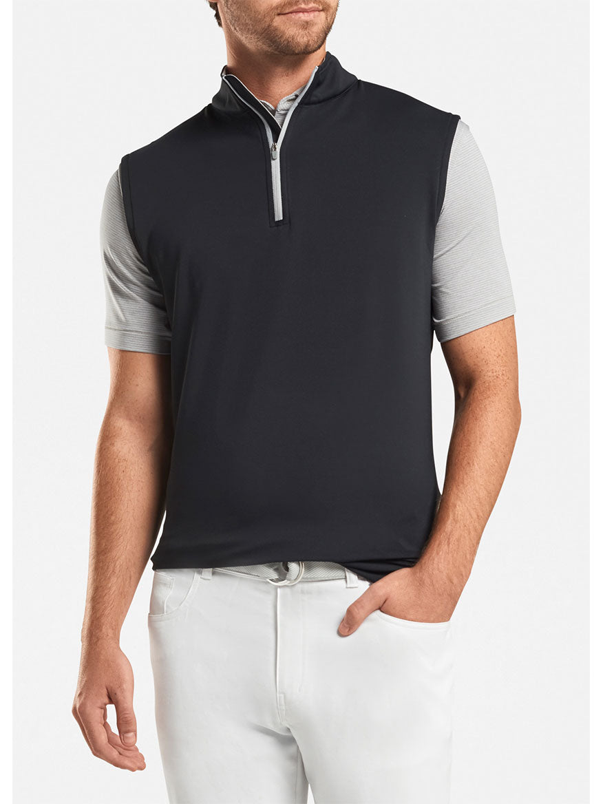 A man wearing a Peter Millar Galway Performance Quarter-Zip Vest in Black and white pants.