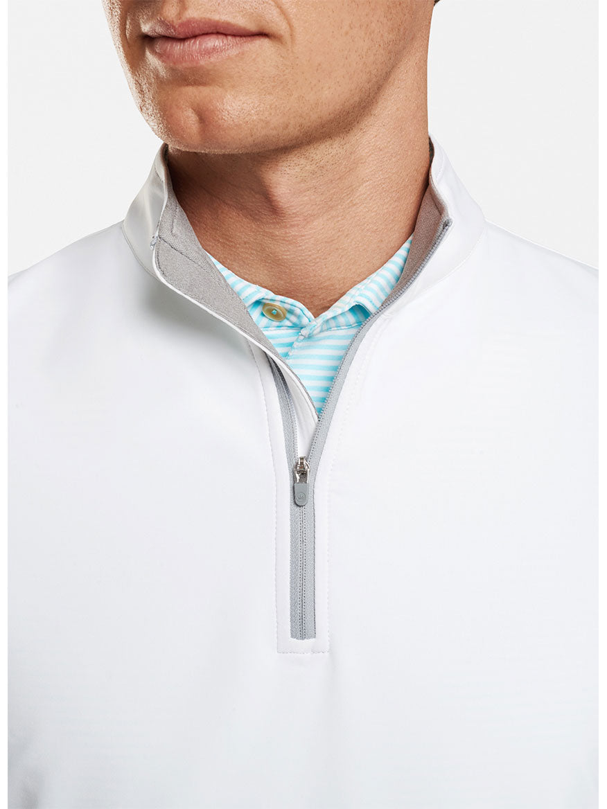 A man wearing a Peter Millar Galway Performance Quarter-Zip Vest in White with a striped collar, featuring moisture-wicking fabric for optimal performance.