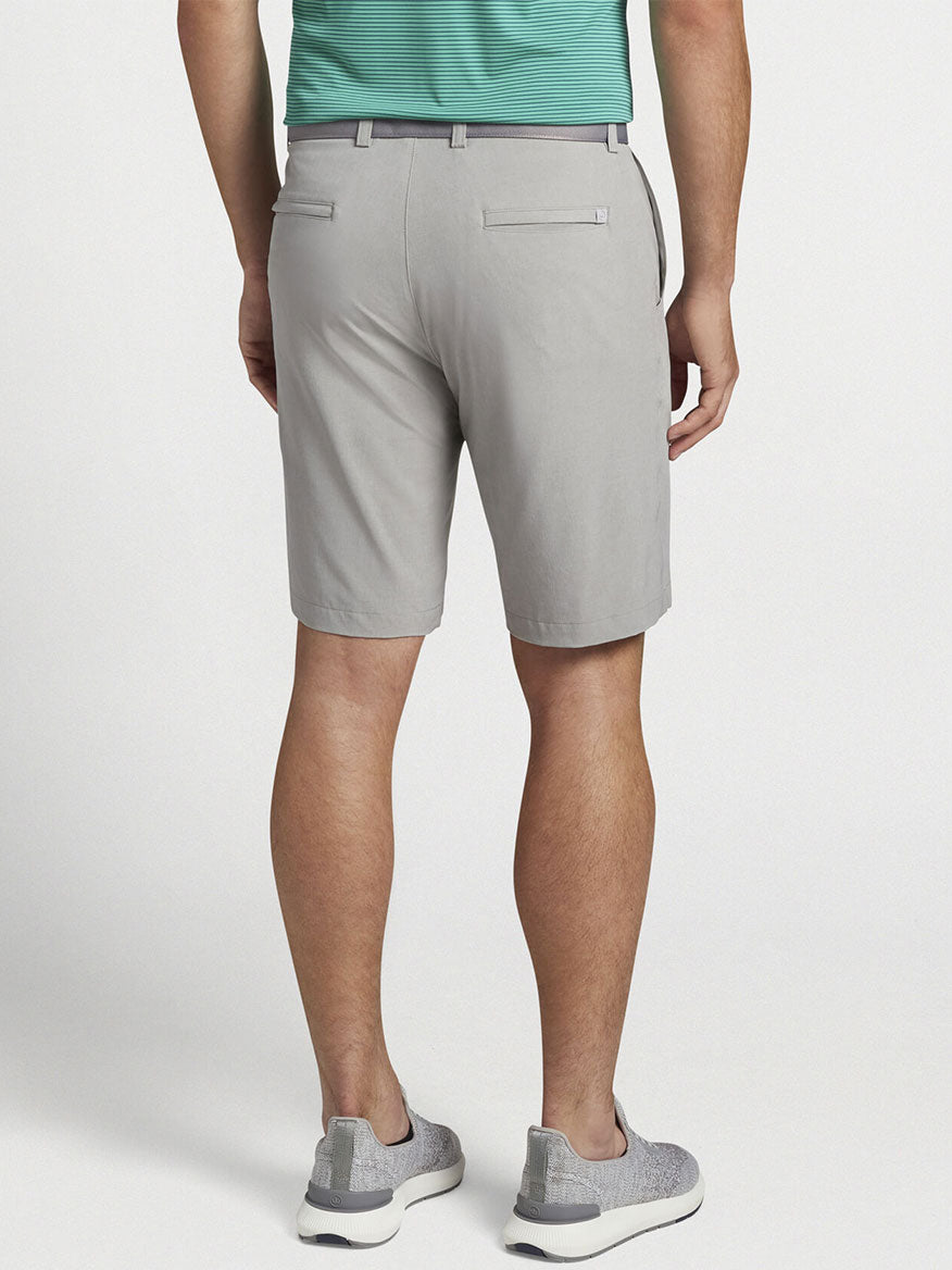 The man wearing the Peter Millar Shackleford Performance Hybrid Short in British Grey showcases the versatility of his four-way stretch performance fabric.