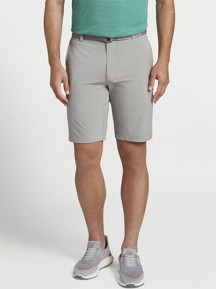 The man is wearing a Peter Millar Shackleford Performance Hybrid Short in British Grey made from performance fabric.