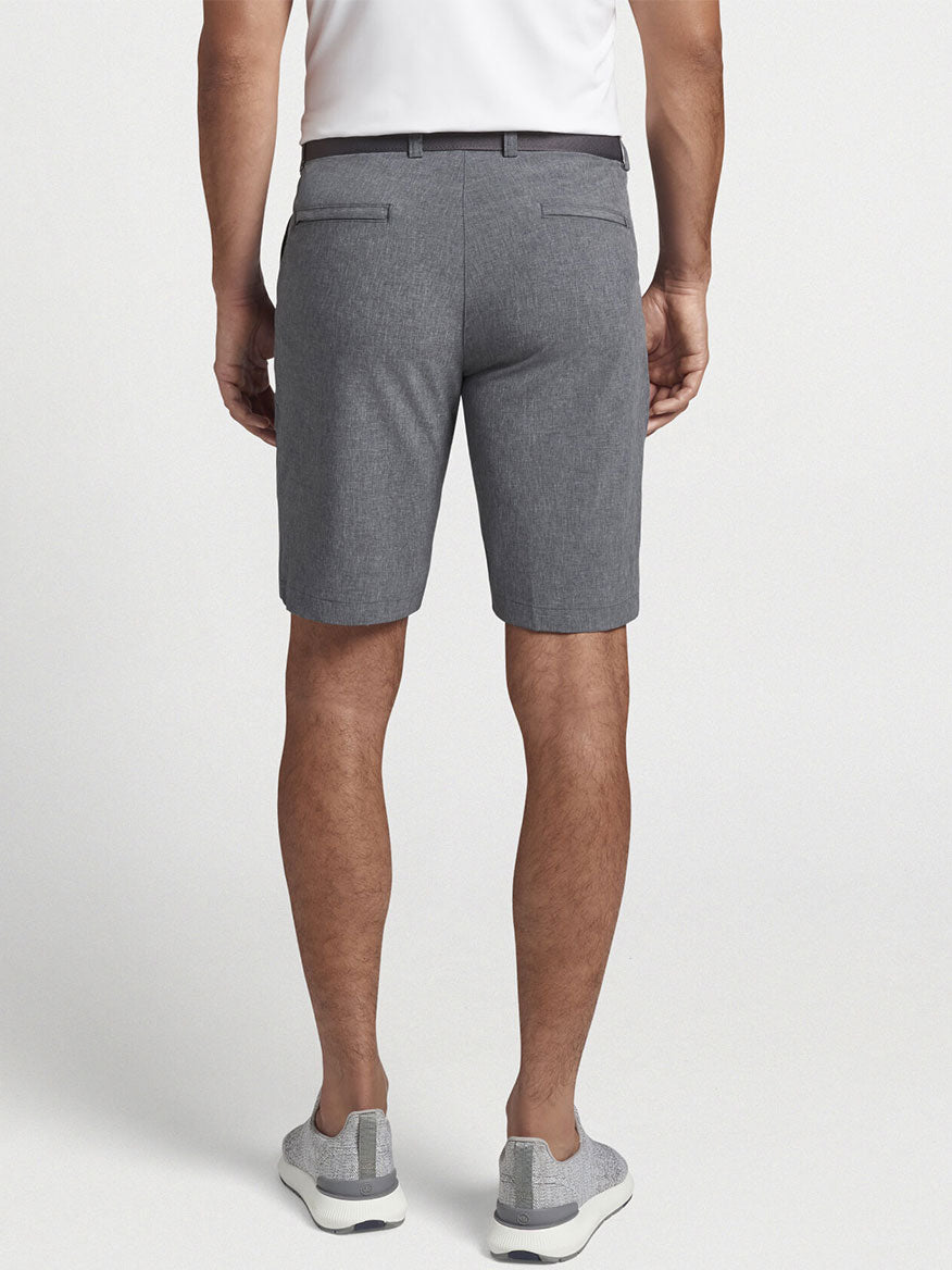 The versatile man's back view wearing the Peter Millar Shackleford Performance Hybrid Short in Iron with a 10" inseam crafted from performance fabric.