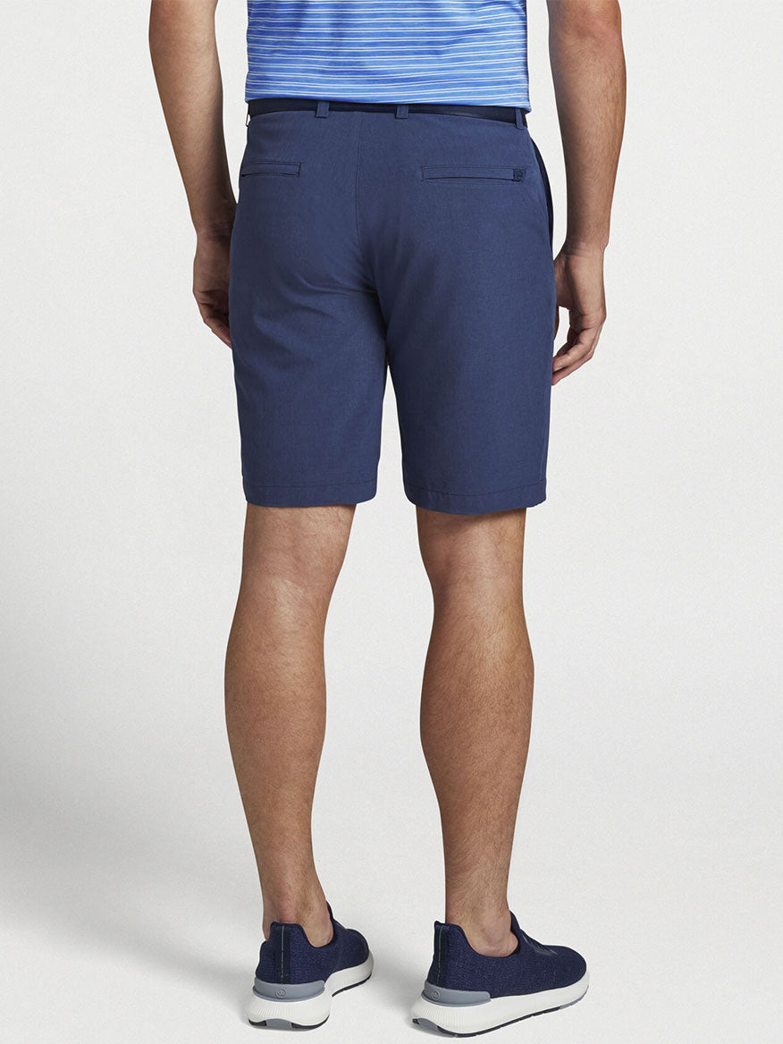 The back view of a man wearing Peter Millar Shackleford Performance Hybrid Short in Navy swim trunks.