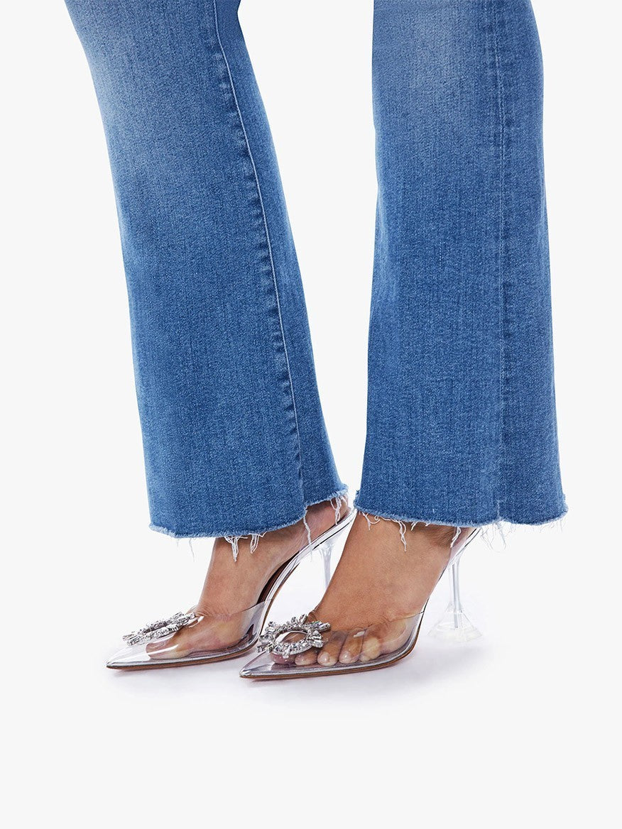 Woman wearing Mother Denim The Weekender Fray in A Groovy Kind of Love mid-rise flare jeans and embellished transparent high heels.
