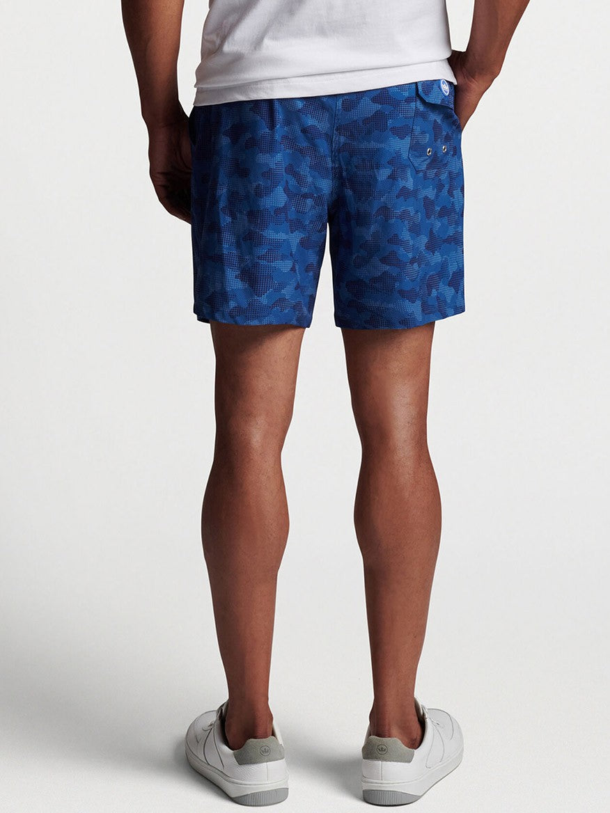 Man wearing blue patterned Peter Millar Camouflaged Coastline Swim Trunk in Navy and white sneakers.