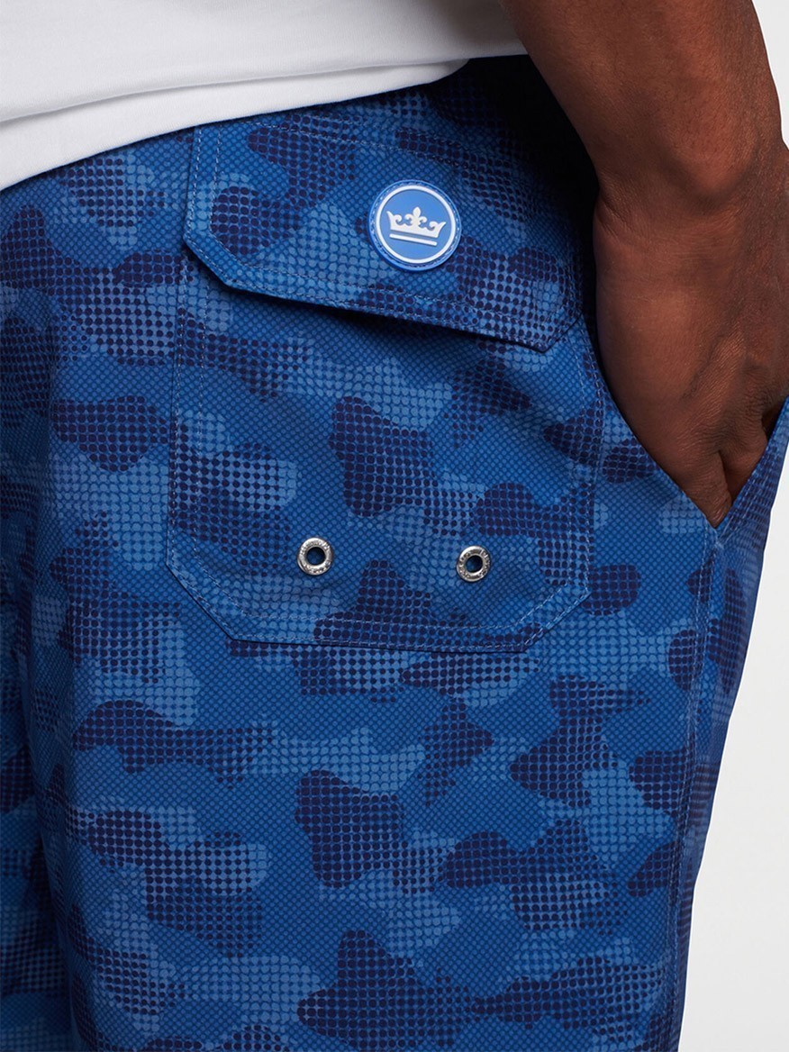 Close-up of a blue camo-patterned Peter Millar Camouflaged Coastline Swim Trunk in Navy pocket with a logo patch.