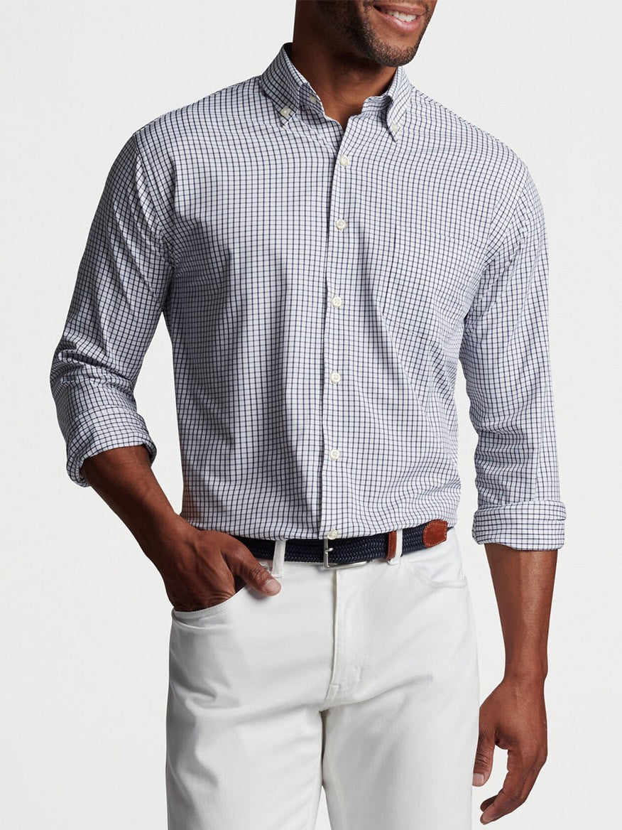 Man wearing a Peter Millar Hanford Performance Twill Sport Shirt in Navy in a checkered pattern and white pants with a black belt.