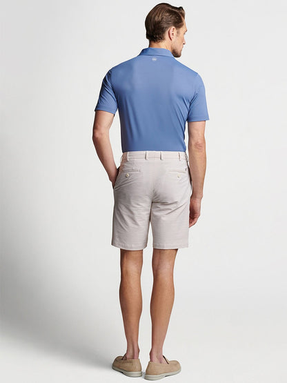 The back view of a man wearing the Peter Millar Matlock Seersucker Performance Short in Summer Dunes and a blue shirt, showcasing his warm-weather appeal.