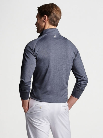Rear view of a man wearing a Peter Millar Stealth Performance Quarter-Zip in Steel and white pants.