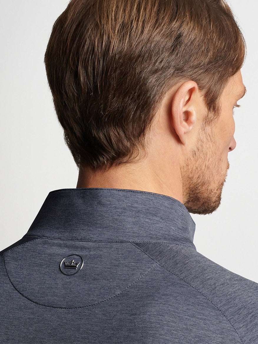 Man wearing a Peter Millar Stealth Performance Quarter-Zip in Steel with a buttoned collar from a rear side-view angle.