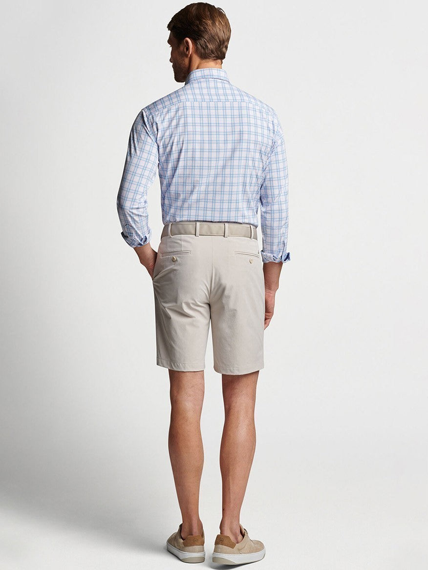 Man standing with his back to the camera wearing a Peter Millar Surge Performance Short in Oatmeal and beige shorts.