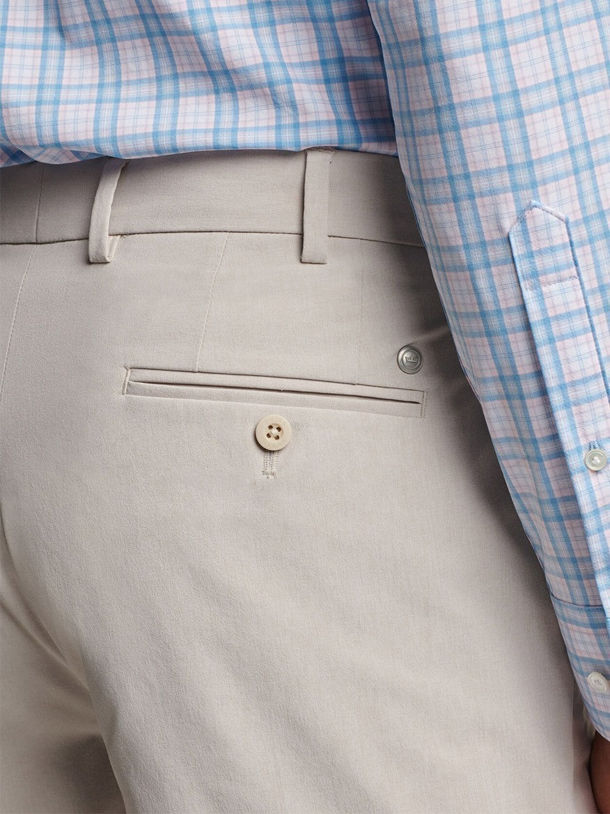 Close-up of a person wearing a Peter Millar Surge Performance Short in Oatmeal with water-resistant protection, featuring a visible belt loop and buttoned back pocket.